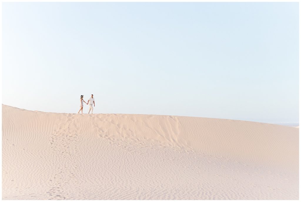 Wide shot of couple walking on the crest of a sand dune at Glamis Sand Dunes.