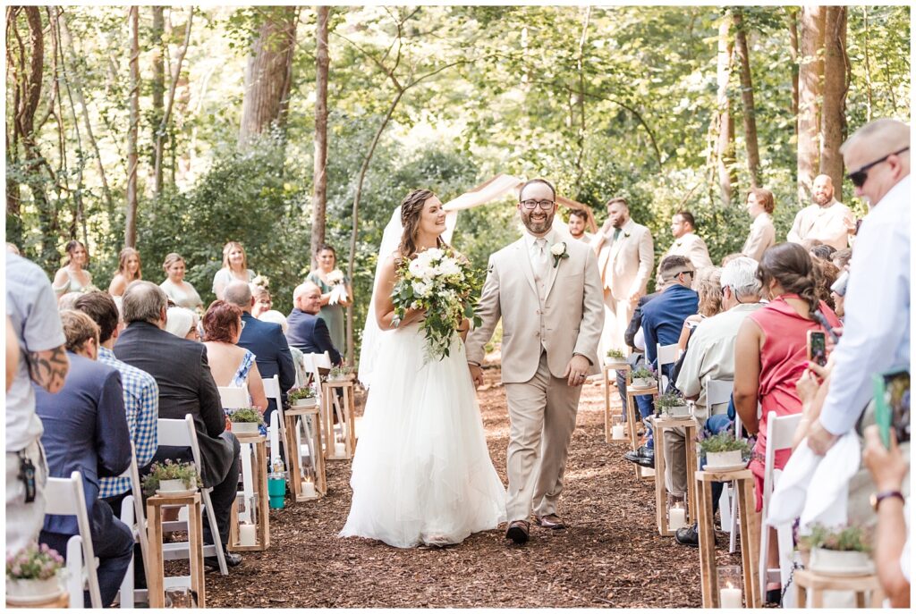 Bride and groom leave their woodland wedding ceremony as husband and wife