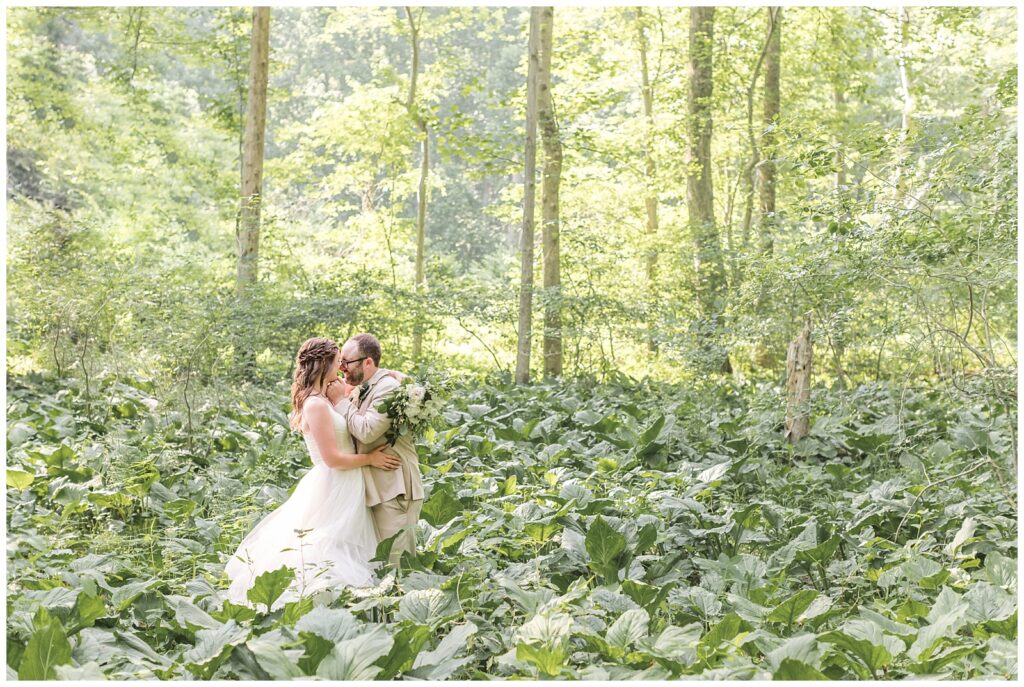 Bride and groom kissing each other in a sunlit forest grove