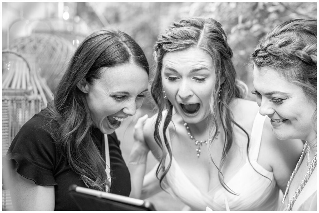 Photographer shares a sneak peek of wedding photos with the bride and matron of honor at the reception