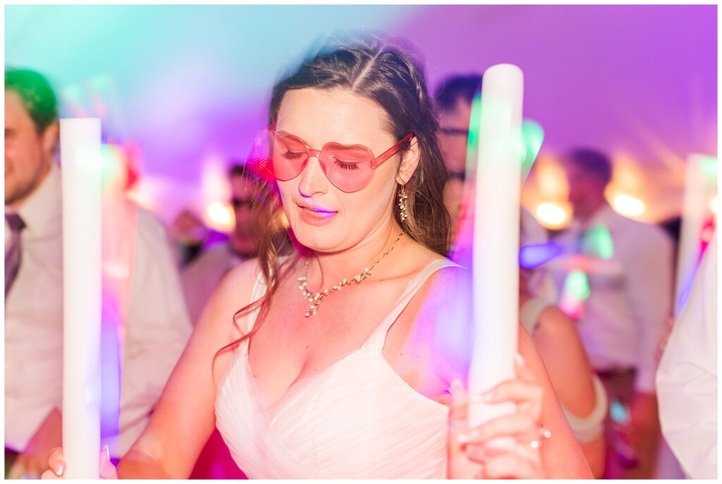 Psychedelic shot of bride and guests dancing with neon glow sticks 