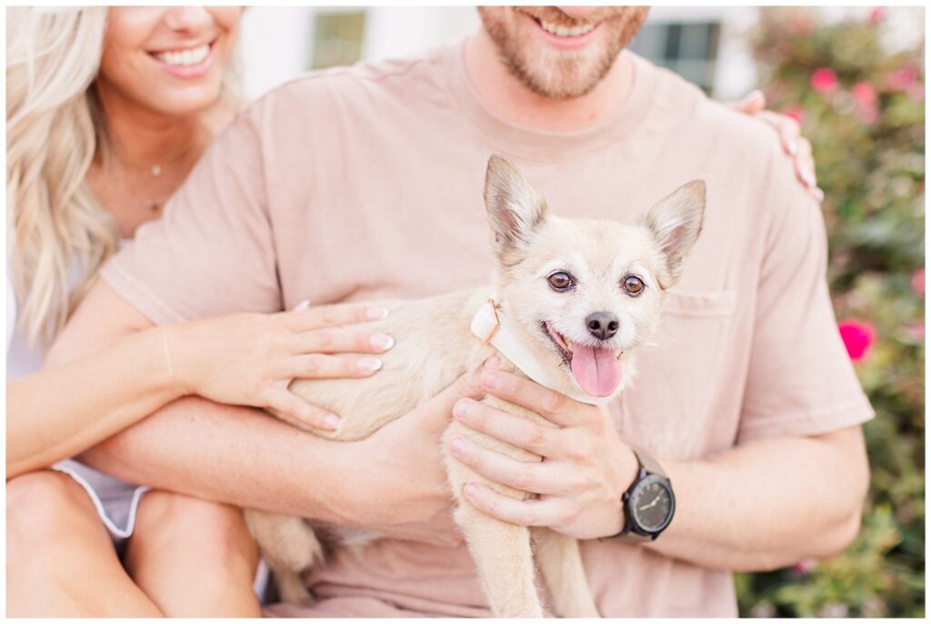 Close up of couple holding dog sitting on a picnic table holding their dog