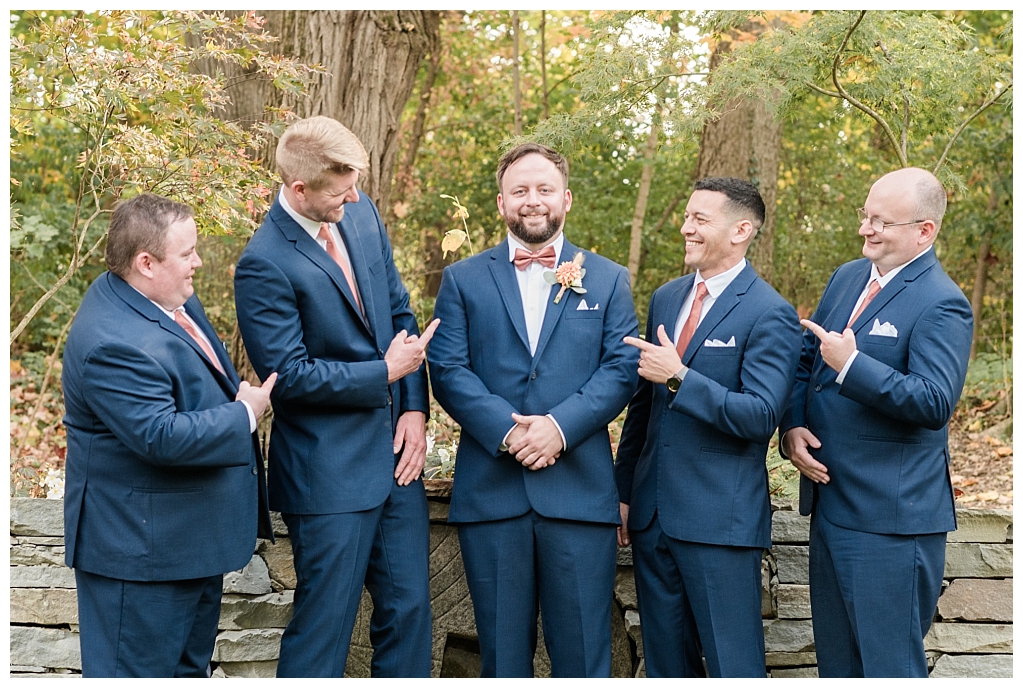Groom and groomsmen in front of rustic paths of  autumn foliage