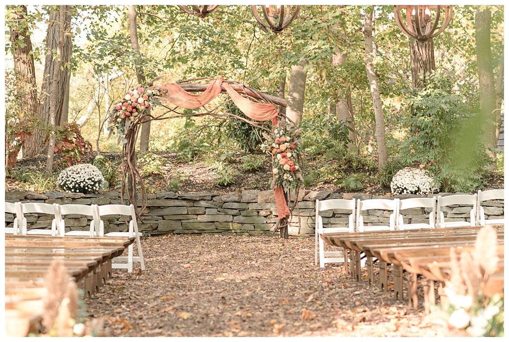 Autumn-inspired decor and wooden arch at woodlands ceremony site at The Stone Mill Inn