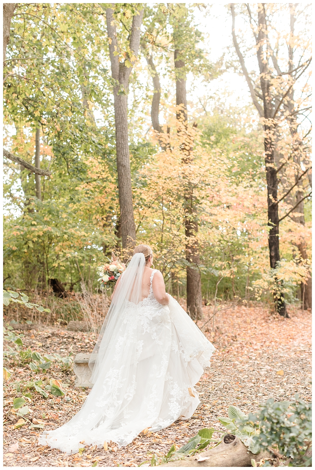 Bride walking through rustic paths of  autumn foliage